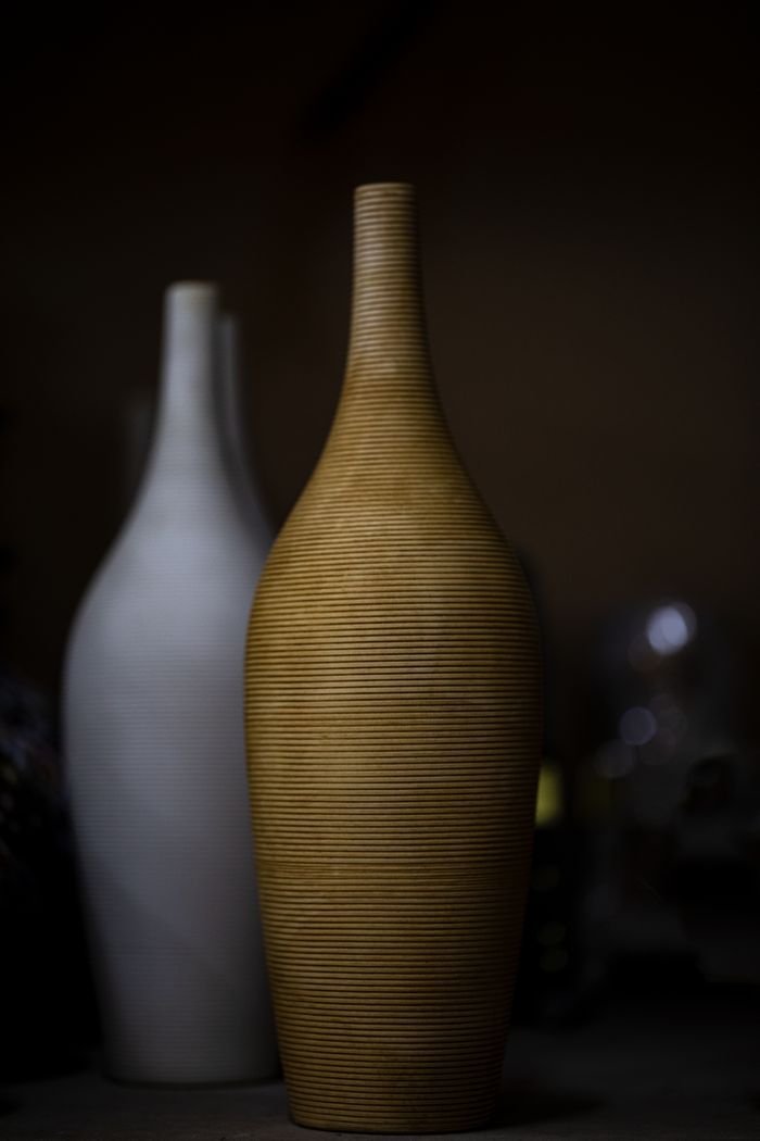 Artistic display of ceramic vases with moody lighting, highlighting texture and form.