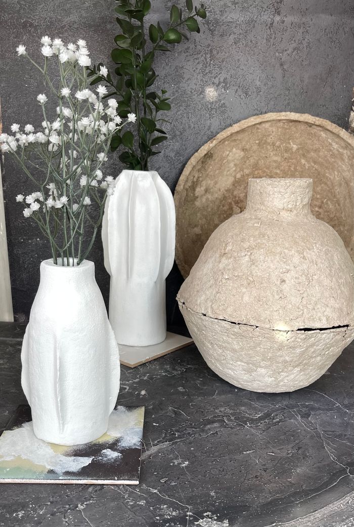 Minimalist ceramic vases and dried flowers on a textured tabletop creating a modern artistic ambiance.